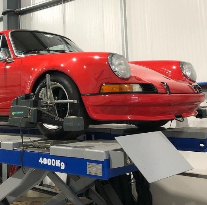 Porsche 911 on alignment rack with suspension components